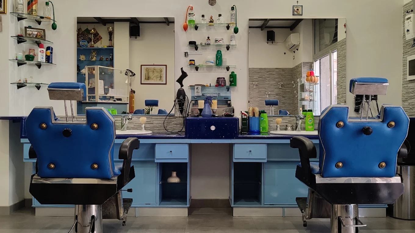 L'interno di Gerardo Barber Shop: due poltrone da barbiere in pelle blu davanti agli specchi